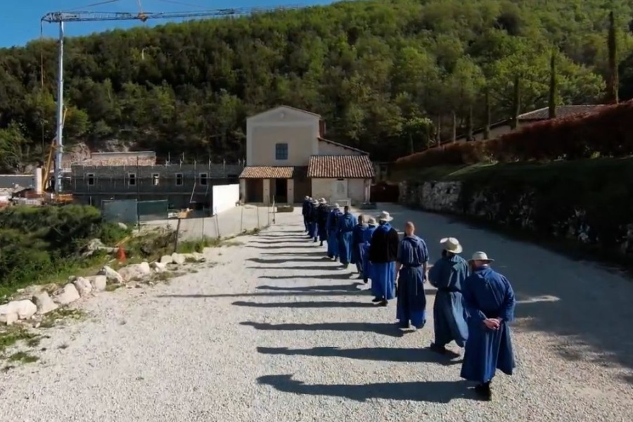 Bencés szerzetesek Norciában sétálnak egy daru felé, amely a monostorukat építi
