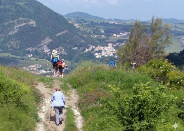 Zarándokok sétálnak egy dombon, a háttérben magas hegyek