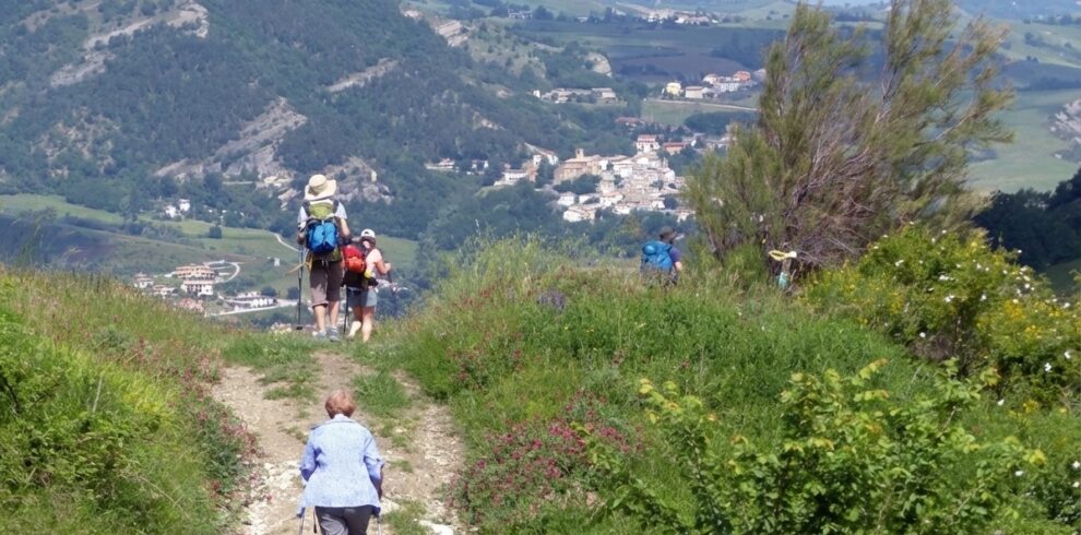 Zarándokok sétálnak egy dombon, a háttérben magas hegyek