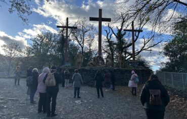 Emberek néznek egy életnagyságú keresztrefeszítési jelenetet Lourdes-ban